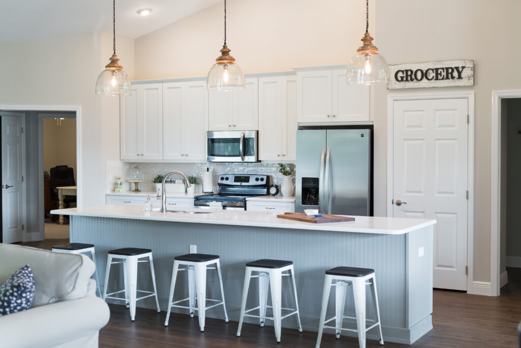 Modern farmhouse kitchen with large island, bar seating, pendant lighting, and white cabinetry