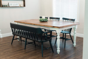 Farmhouse dining room with wood table, bench seating, and black chairs on hardwood floors