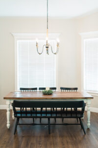 Farmhouse dining area with wood table, chandelier lighting, and large windows with natural light