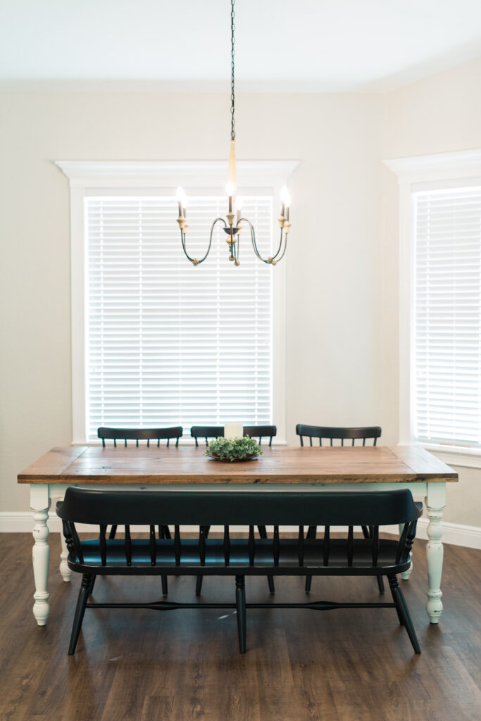 Farmhouse dining area with wood table, chandelier lighting, and large windows with natural light