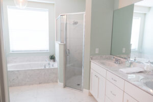 Farmhouse bathroom with glass walk-in shower, soaking tub, and marble finishes