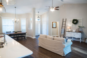 Open concept farmhouse living room with high ceilings, natural light, and connected dining and kitchen areas