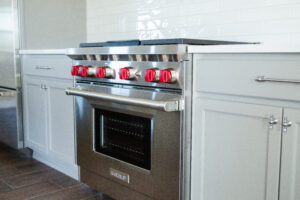 professional gas range with red knobs and custom cabinetry kitchen