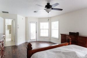 Bedroom with large windows and ceiling fan in custom home