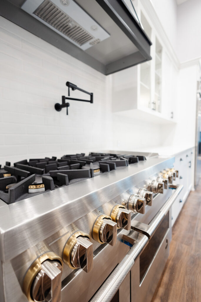 close up of professional gas range with brass knobs in farmhouse kitchen