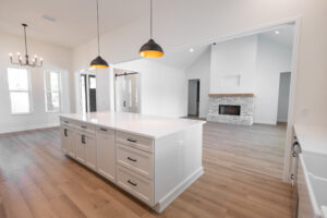Custom kitchen island overlooking the vaulted great room and brick fireplace in a Morriston, FL modern farmhouse