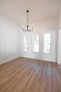Bright dining room with black chandelier and wood-look flooring in a custom modern farmhouse in Morriston, FL