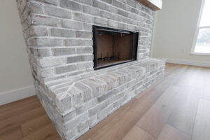 Whitewashed brick fireplace with natural wood mantel in a custom modern farmhouse in Morriston, FL