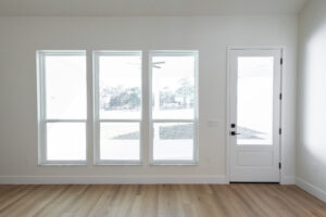 Great room with a bank of windows and a glass exterior door opening to the acreage in a Morriston, FL custom farmhouse