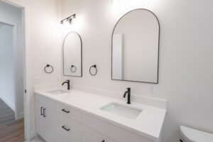 Bathroom double vanity with arched mirrors and matte black faucets in a custom farmhouse in Morriston, FL