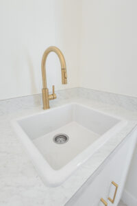 Laundry room with gold faucet, farmhouse sink, and marble countertop in a Morriston, FL custom farmhouse