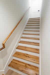 Wood staircase with white risers leading to the upstairs bonus room in a two-story custom farmhouse in Morriston, FL