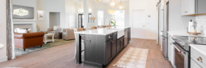 Spacious custom kitchen with black island, farmhouse sink, and view into a bright living room in a Curington Home in Ocala, Florida