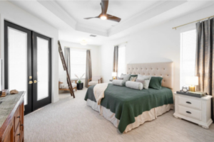 Serene primary bedroom with tufted headboard, French doors, and accent seating in a Curington Homes custom build