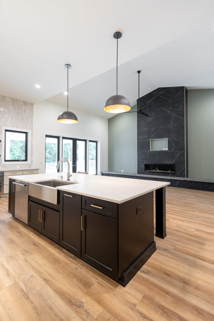 Open-concept kitchen with a large island, pendant lighting, and modern country-style finishes.