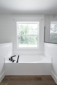 Modern farmhouse bathroom with freestanding white soaking tub and large window in Morriston Florida