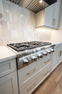 Professional stainless steel gas range with brass-accent knobs in a custom kitchen by Curington Homes in Ocala, Florida