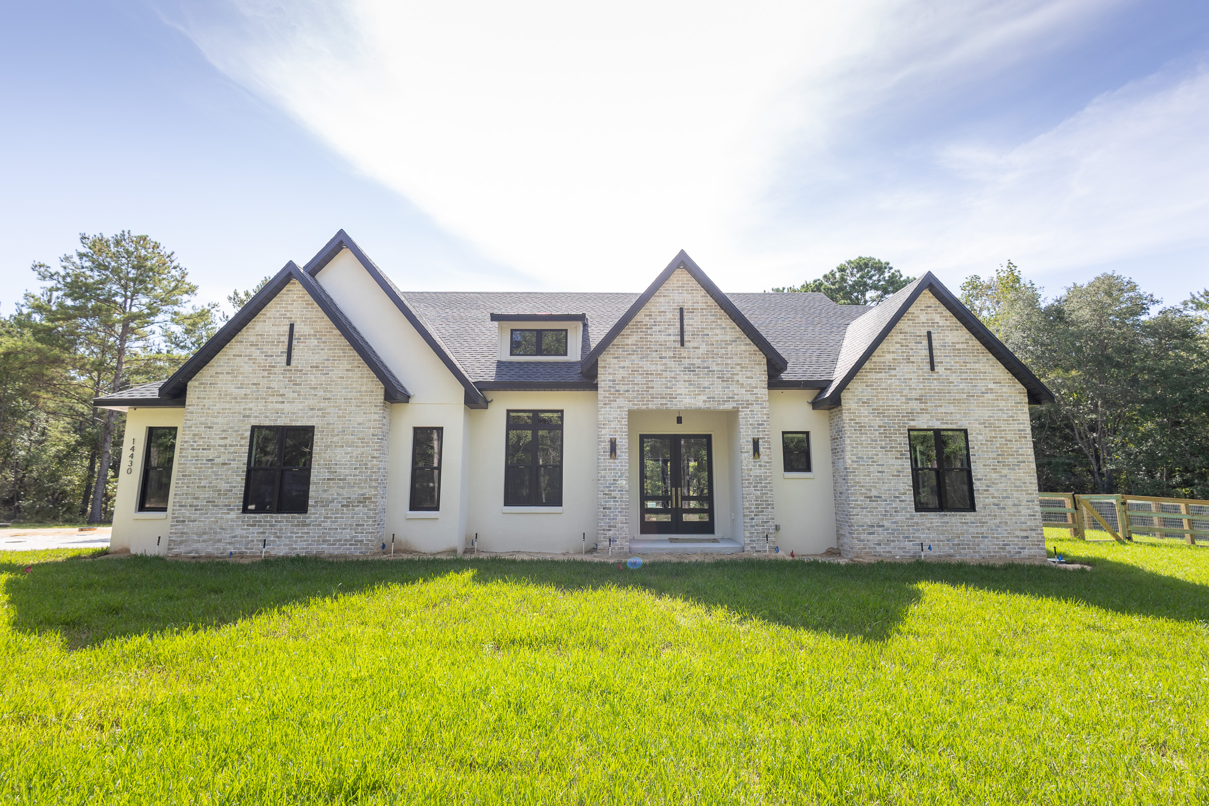 Modern farmhouse custom home exterior in Williston FL built by Curington Homes featuring black windows and gabled rooflines