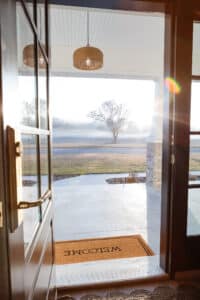 View from inside a country-style home looking out through the front door toward open land and natural scenery.