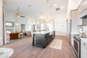 Spacious custom kitchen with black island, farmhouse sink, and view into a bright living room in a Curington Home in Ocala, Florida