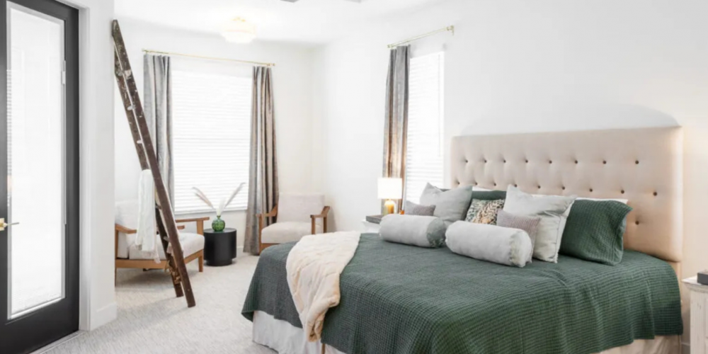 Serene primary bedroom with tufted headboard, French doors, and accent seating in a Curington Homes custom build