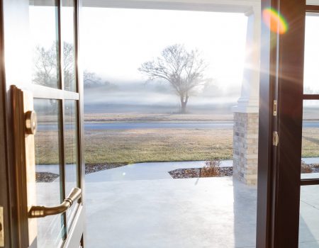 View from inside a country-style home looking out through the front door toward open land and natural scenery.