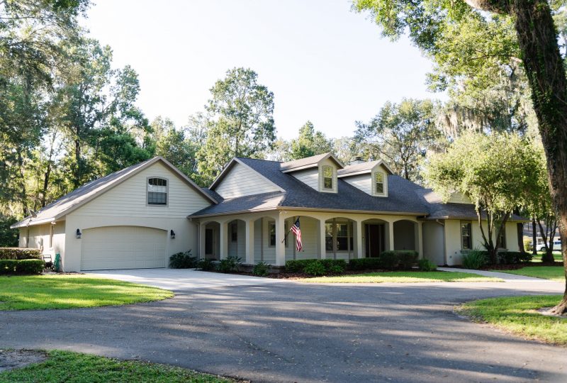 Country-style home with circular driveway, detached garage, and landscaped yard.