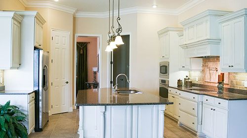 A kitchen island set in a modern farmhouse kitchen with stainless steel appliances and granite counter tops.