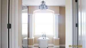 A clawfoot bathtub sits under a large window in this modern farmhouse bathroom.