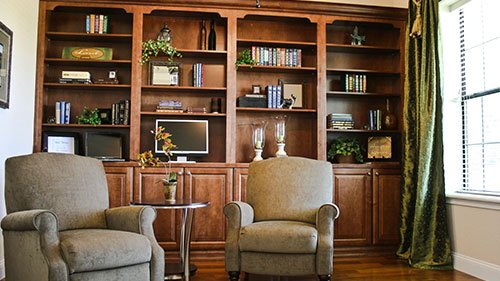 Two chairs sit under library built-ins in this modern farmhouse study.